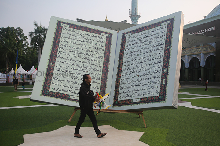 Seorang warga melewati replika Al-Quran raksasa di halaman Masjid Al-Azhom, Kota Tangerang, Banten, Selasa (9/7/2024). (Foto: Edwin B/ Muslim Obsession)