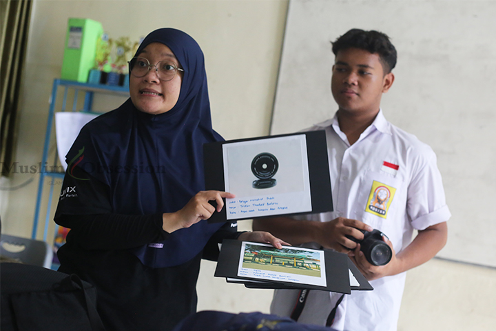 Pelatih ekskul fotografi Riana Mentarijuita (Kiri) menunjukkan hasil karya foto siswa Sekolah Menengah Pertama (SMP) Negeri 271, Jakarta Barat, Kamis (25/7/2024). (Foto: Edwin B/ Muslim Obsession)