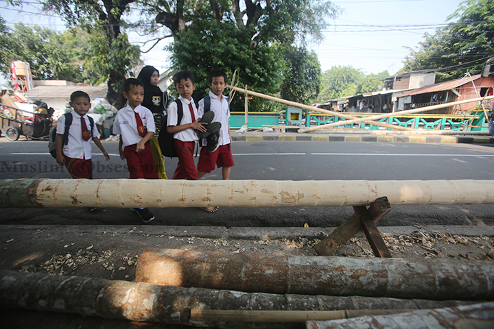 Sejumlah anak melintasi batang pohon panjat pinang di Kawasan Manggarai, Jakarta, Senin (12/8/2024). (Foto: Edwin B/ Muslim Obsession) 