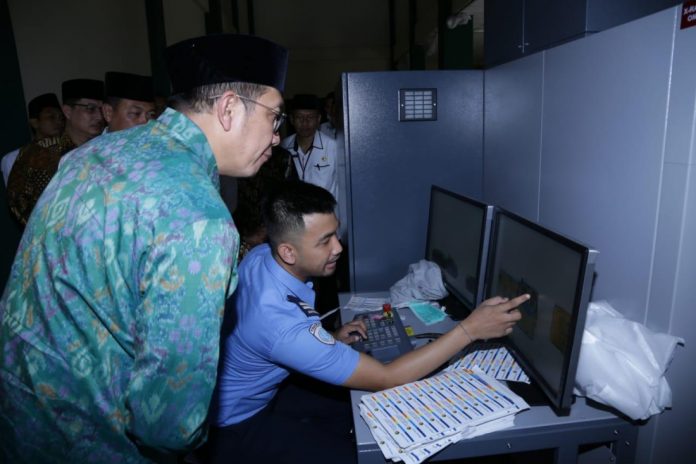 Menag mengamati monitor xray koper jamaah calon haji embarkasi Palembang, Kamis (11/07).